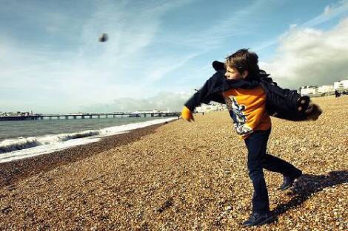 海辺で石を投げる少年の画像