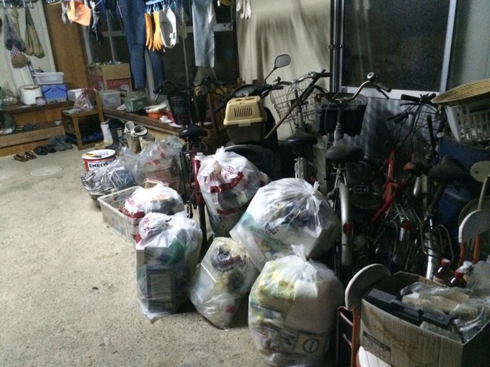 ゴミ袋と乗らない自転車が積み上がった実家のガレージの画像